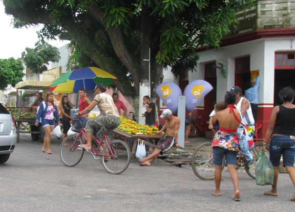 Bikes turn the corner in front of street vendor in Icoaraci.