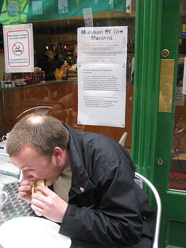 Sign about famine in Zimbabwe, part of the a Nutopia exploring adventure, on window behind the guy and his sandwich.
