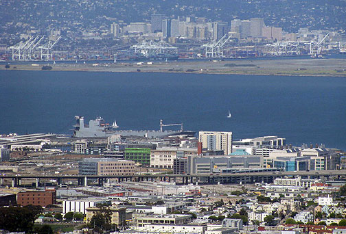 From Twin Peaks you can see two dominant industries that straddle the Bay: past the freeway the new office buildings make up UCSF Mission Bay, a biotech campus, and across the bay is the abandoned Alameda Naval Air Station with the many cranes that dominate the Port of Oakland and have been the linchpin of globalization.