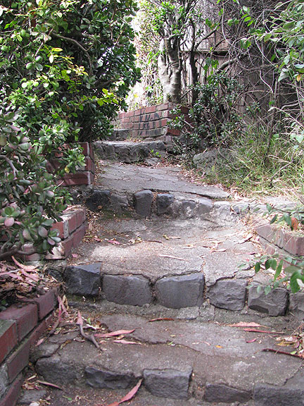 As you climb the stairs become more regular, and at the top you ascend a cement flight and emerge from behind a fence. This path is well hidden!