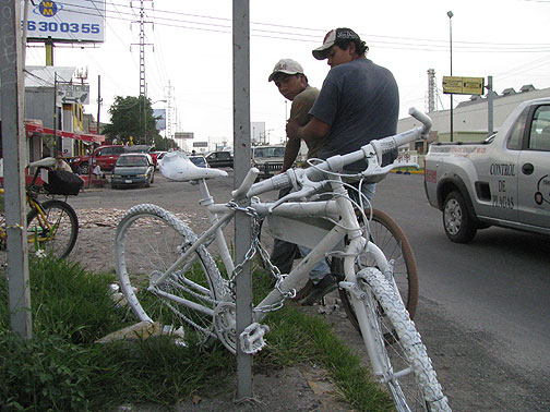 Two workers going home on bike pass a just-installed Ghost Bike.